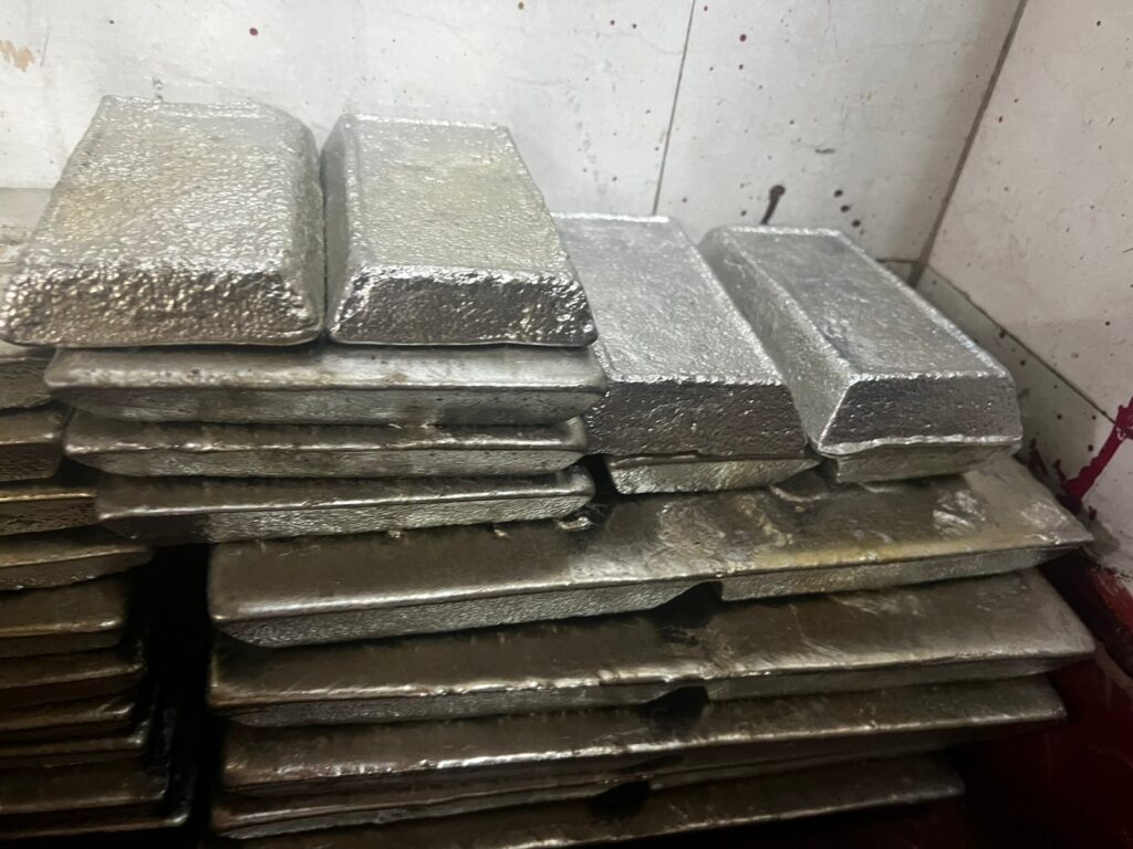 Штабель прямокутних олов'яних чушок біля стіни складу — сировина для прийому як лом олова.